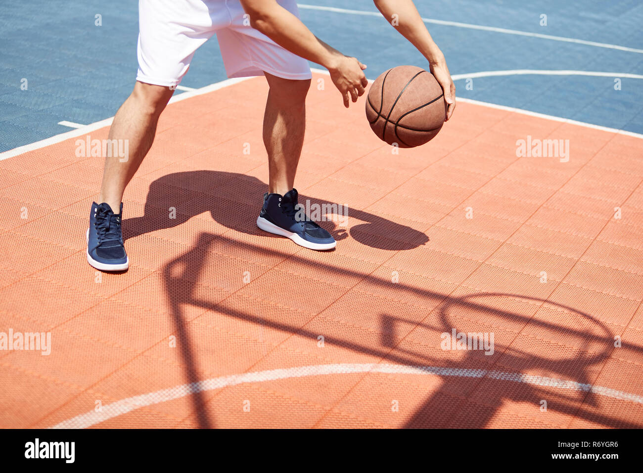 Les jeunes hommes asiatiques pratiquer basket-ball balle de traitement sur les compétences de la cour en plein air. Banque D'Images
