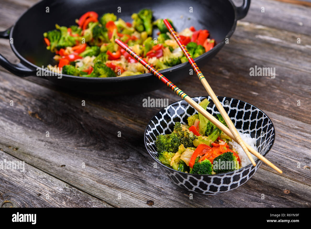 Wok de légumes, bol de riz et baguettes sur sol en bois Photo Stock - Alamy