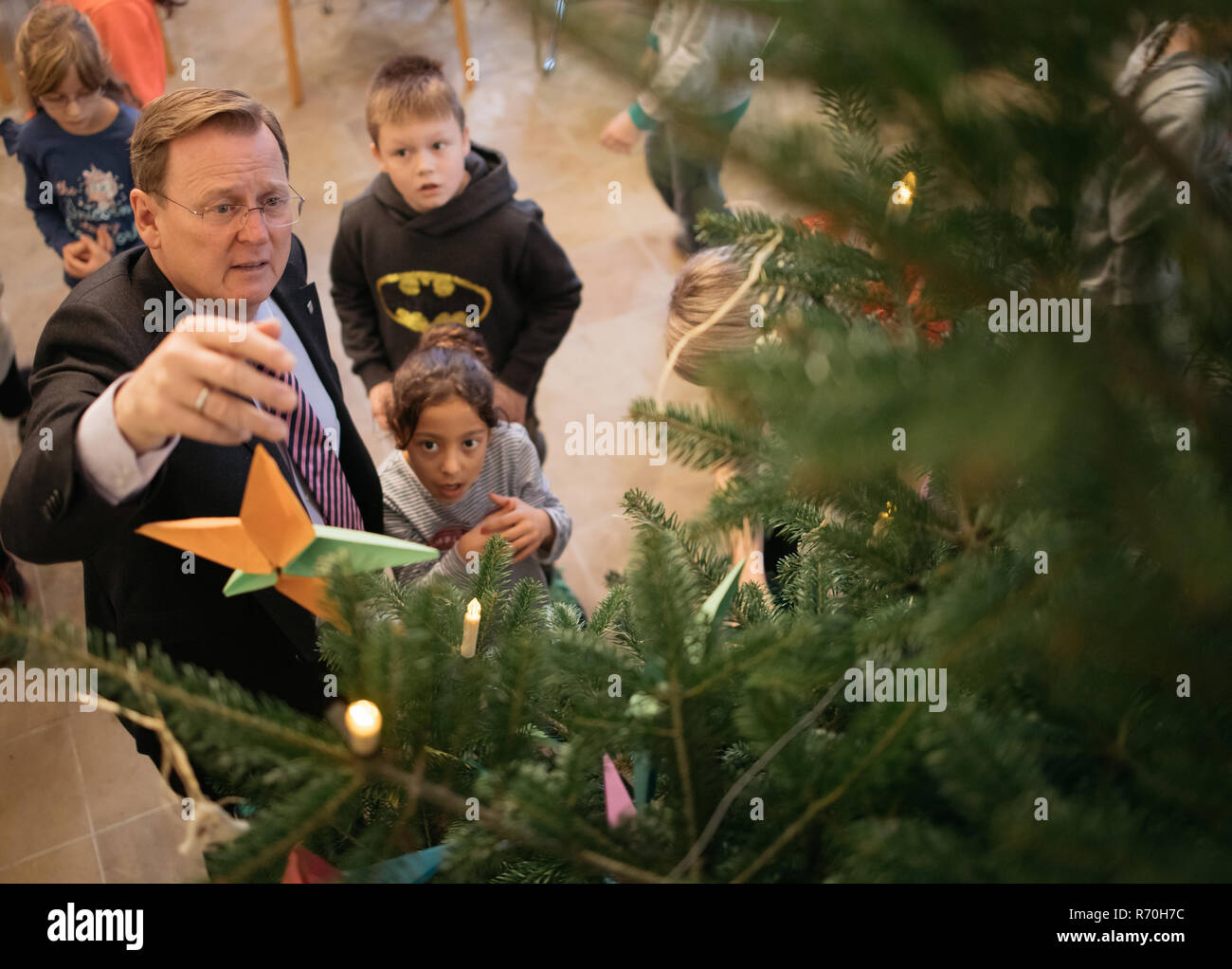 07 décembre 2018, la Thuringe, Erfurt : Bodo Ramelow (gauche), premier ministre de la Thuringe, décore l'arbre de Noël dans la chancellerie d'état de Thuringe, avec les enfants de l'école primaire 'Erfurt sur la prairie Hill'. Avant cela, il a montré les enfants les salles de réception de la chancellerie d'état. Photo : Arifoto Ug/Michael Reichel/dpa Banque D'Images