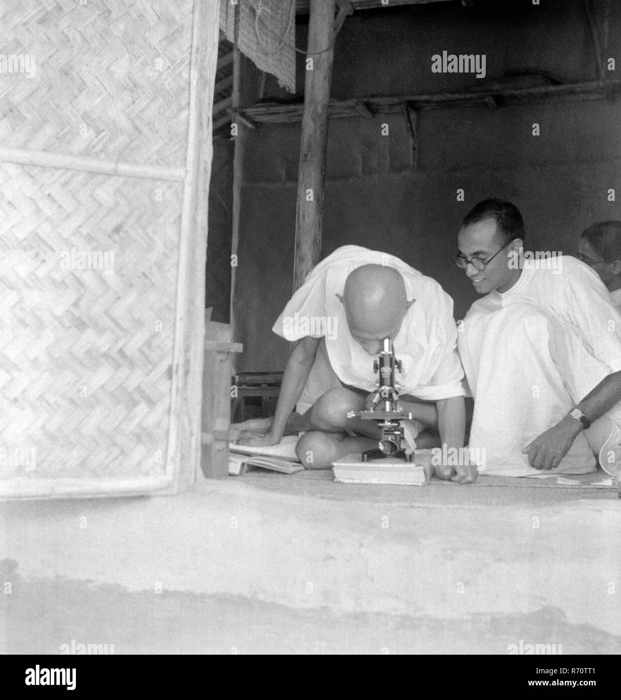 Mahatma Gandhi regardant au microscope observer les germes de la lèpre à Seagram Ashram, Wardha, Maharashtra, Inde 1940, ancienne image millésime 1900 Banque D'Images