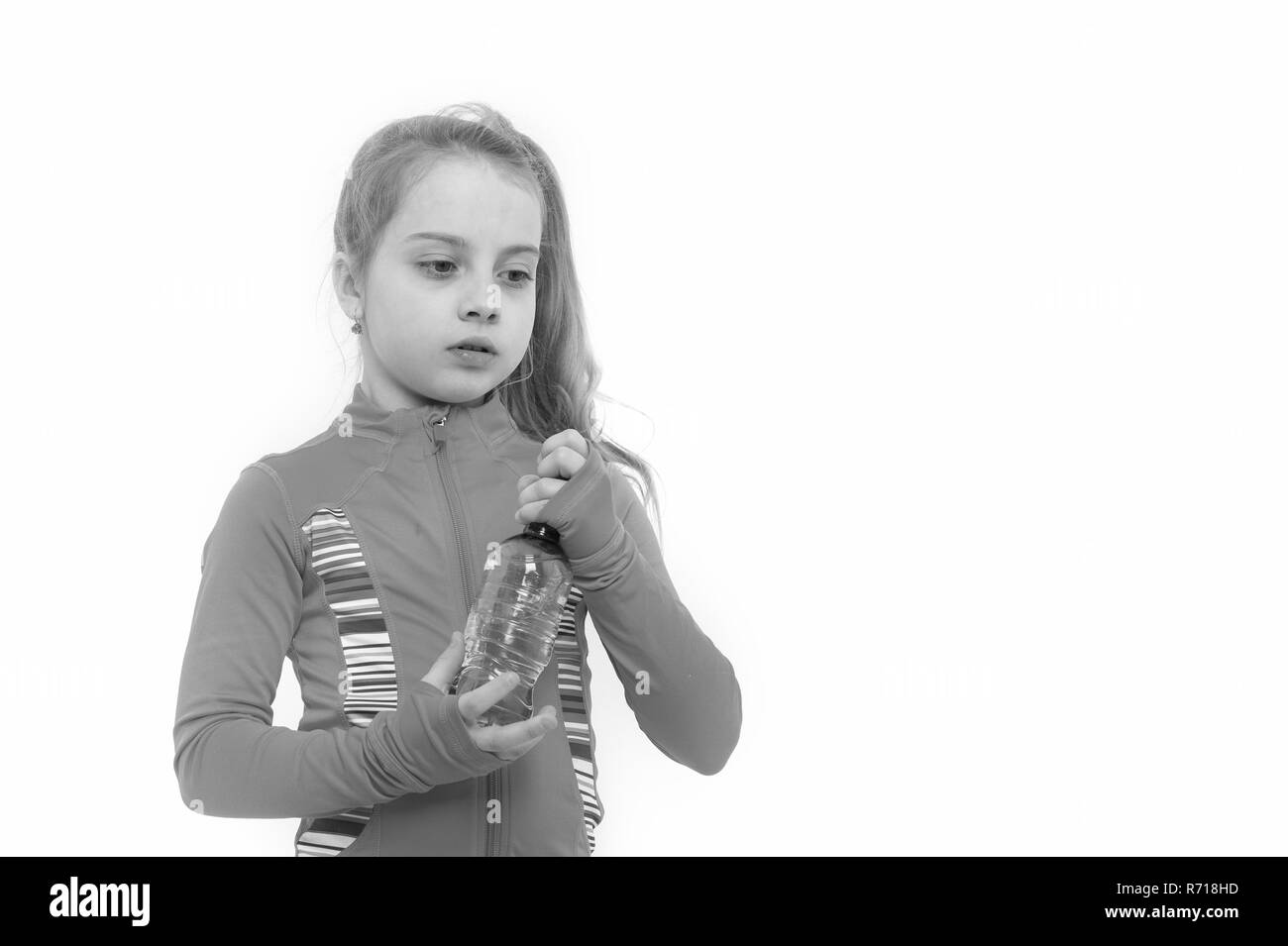 Fille avec bouteille d'eau potable. Soif de l'enfant en costume rose isolé sur blanc. La santé et de boisson saine. La déshydratation, la soif concept. L'équilibre liquide, hydratation, copy space Banque D'Images