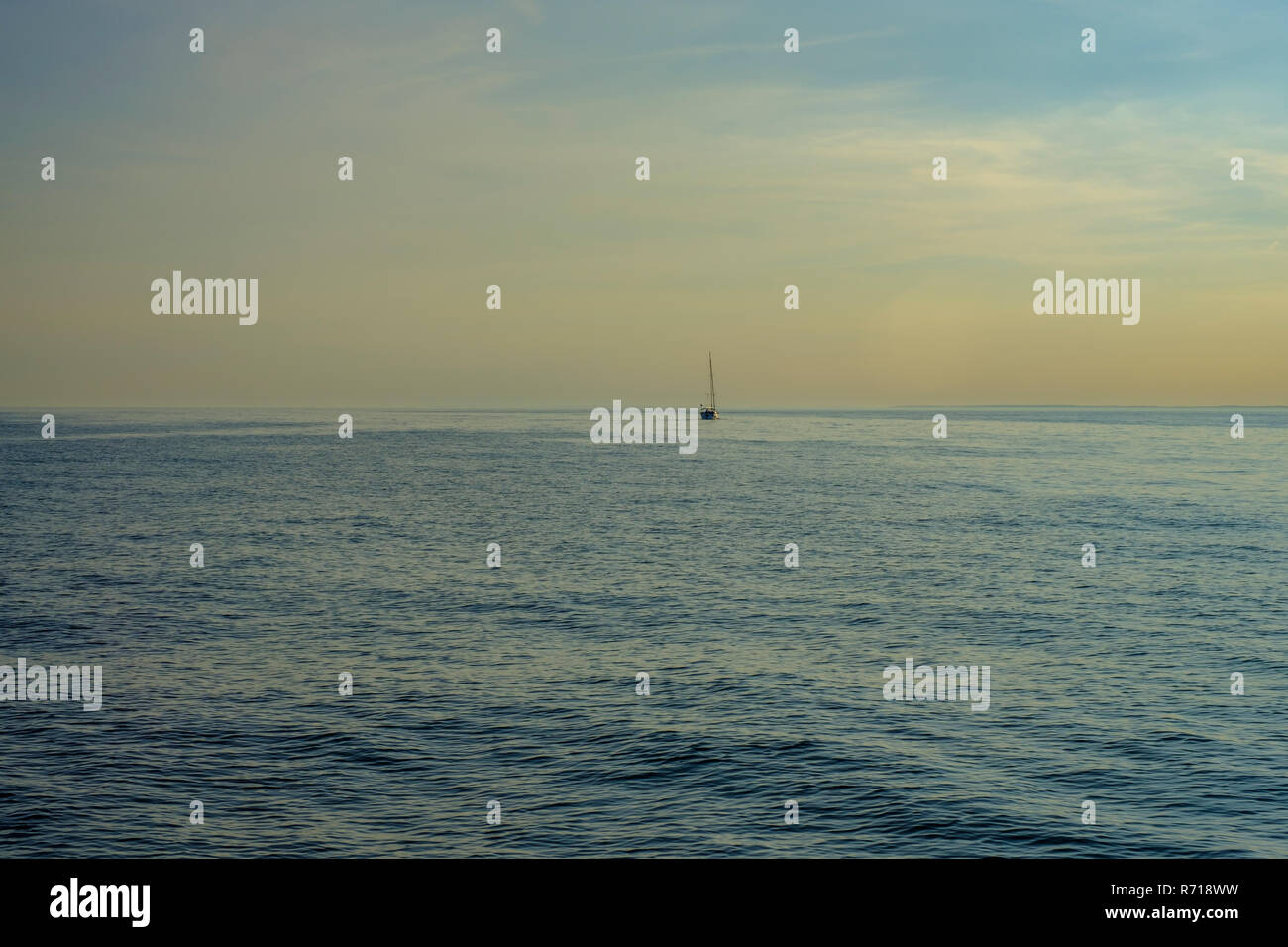 Un bateau à voile sur l'eau libre dans la lumière du soir. Banque D'Images