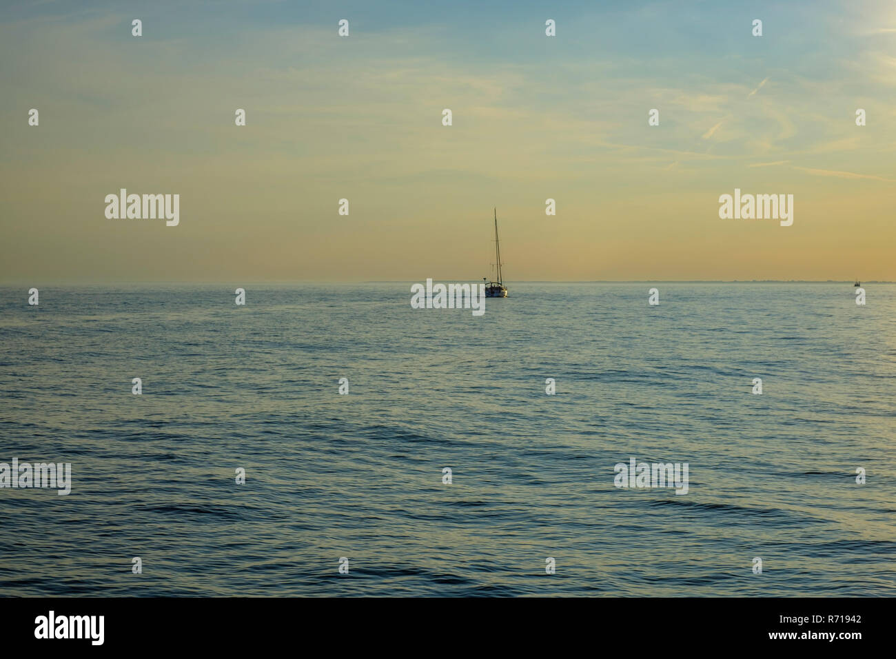 Un bateau à voile sur l'eau libre dans la lumière du soir. Banque D'Images
