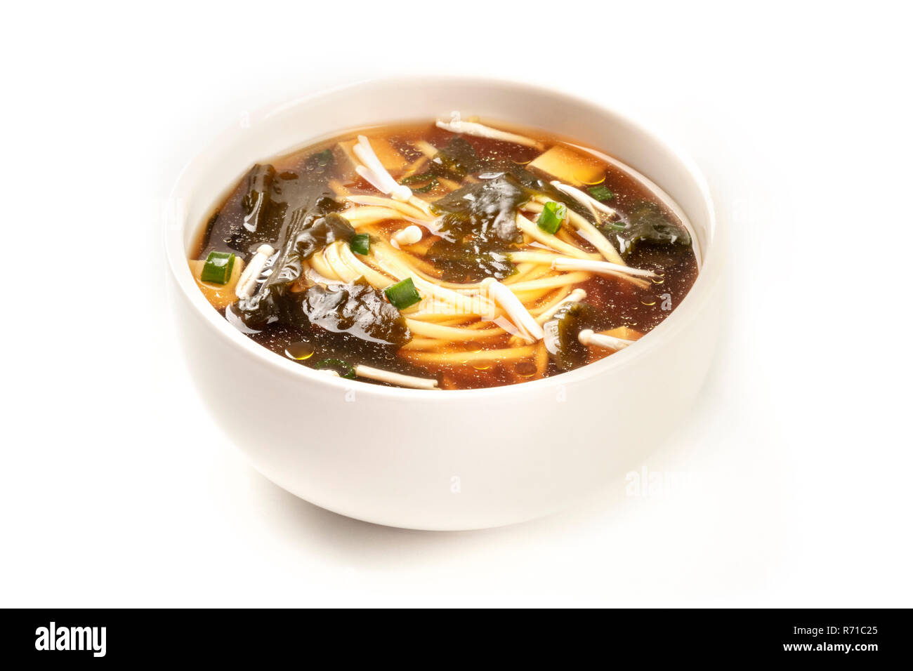 Une photo d'un bol de soupe miso avec le tofu, les oignons verts, les nouilles, les champignons Enoki, wakame et, sur un fond blanc avec une place pour le texte Banque D'Images