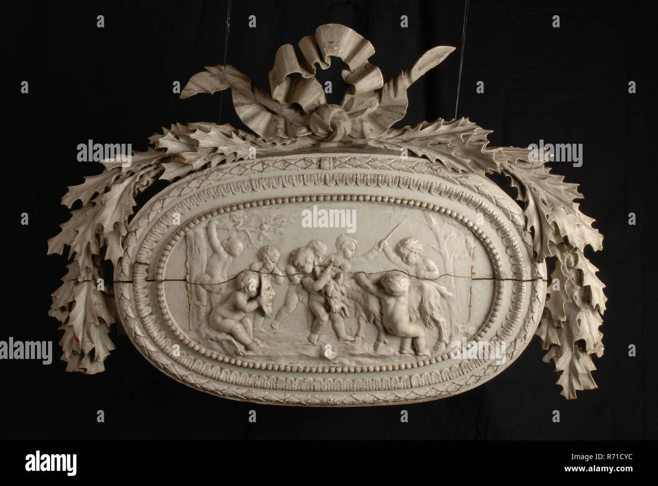 Ornement en bois sculpté avec putti et chèvre, dans cadre ovale, surmonté d'une couronne de feuilles de chêne, ornement sculpture sur bois sculpture peinture plâtre bois matériau visuel, d 16,0 Banque D'Images