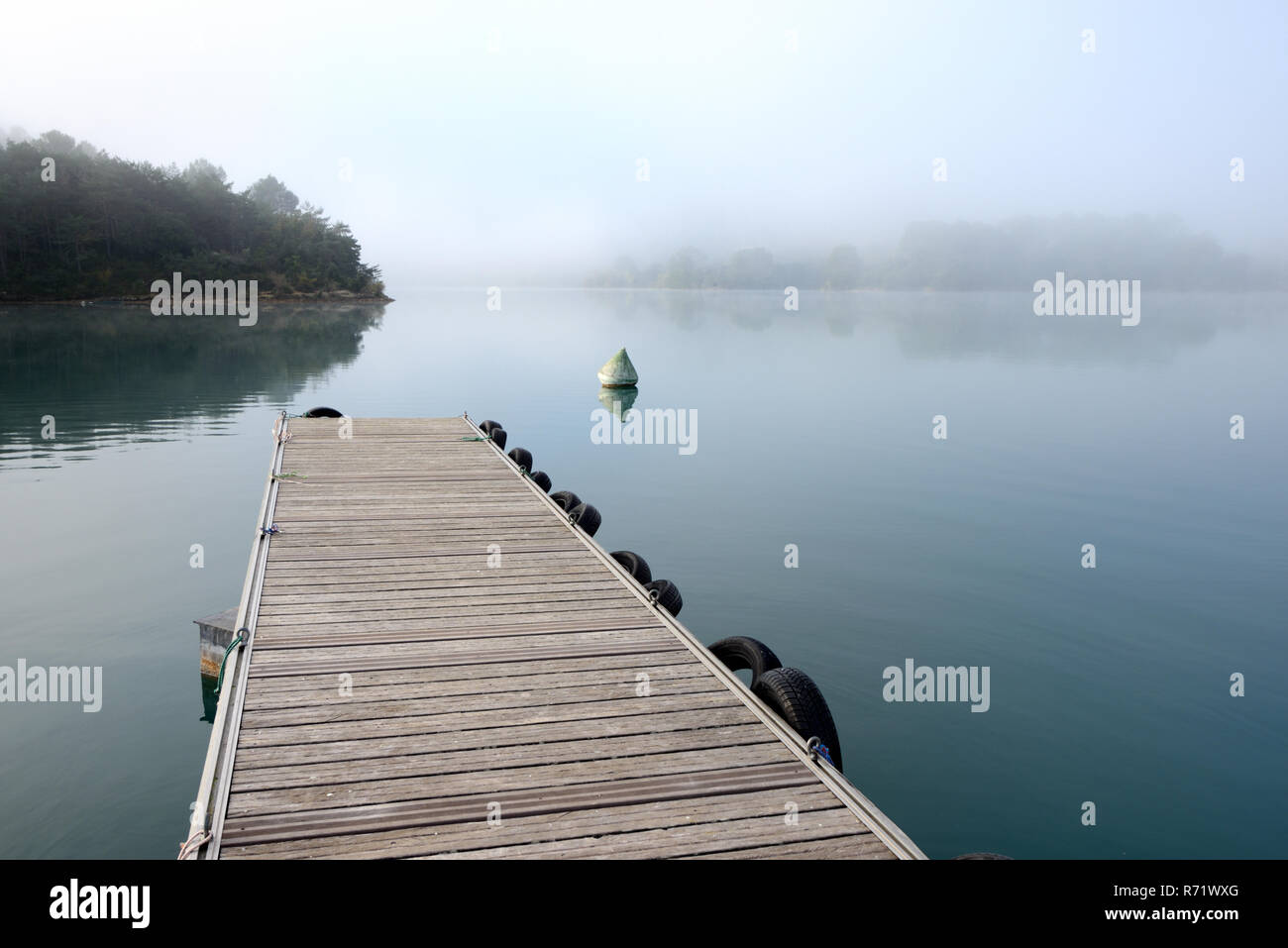 Jetée en bois qui s'avance dans le lac d'Esparron encore brumeux en début de matinée Esparron Provence France Banque D'Images