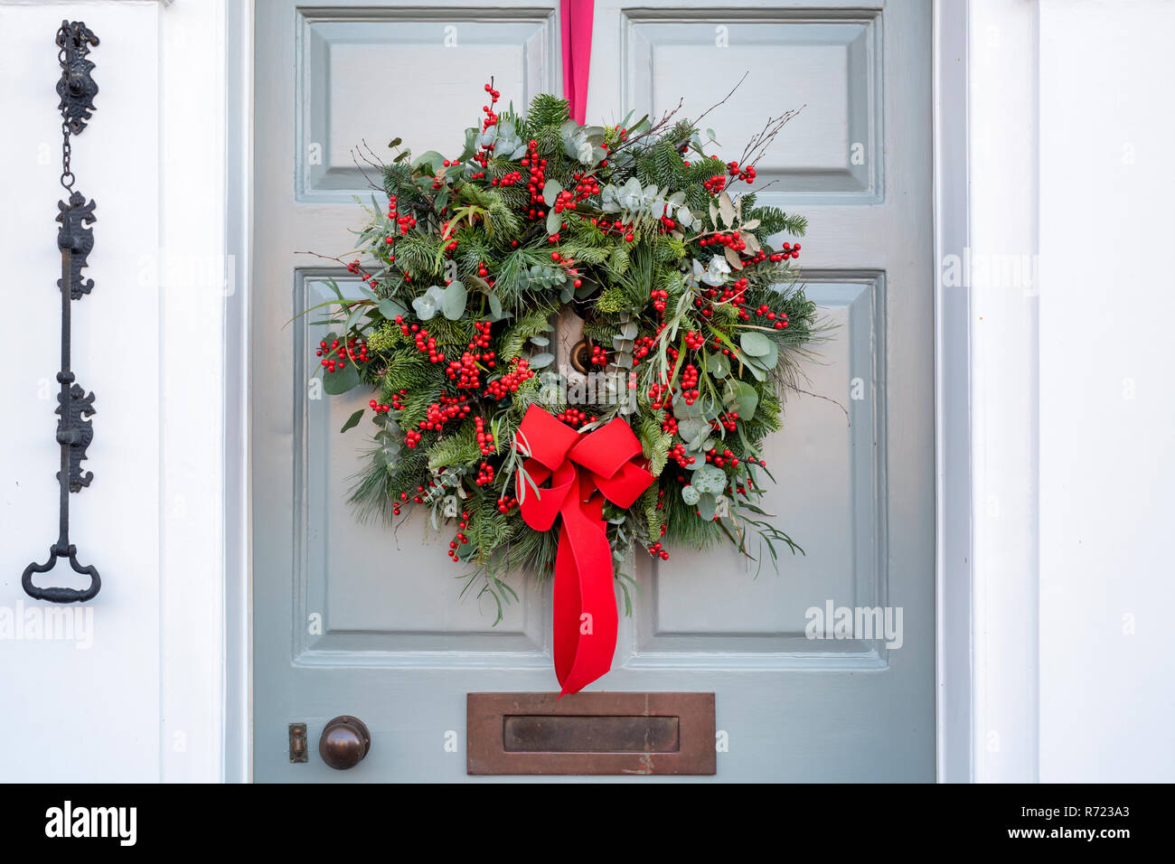 Couronne de Noël avec ruban rouge sur une porte de maison à Broadway. Cotswolds, Worcestershire, Angleterre Banque D'Images