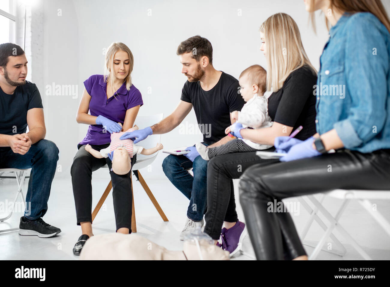 Groupe de personnes au cours de la formation en premiers soins avec moniteur montrant sur mannequin comment faire la respiration artificielle pour le bébé Banque D'Images