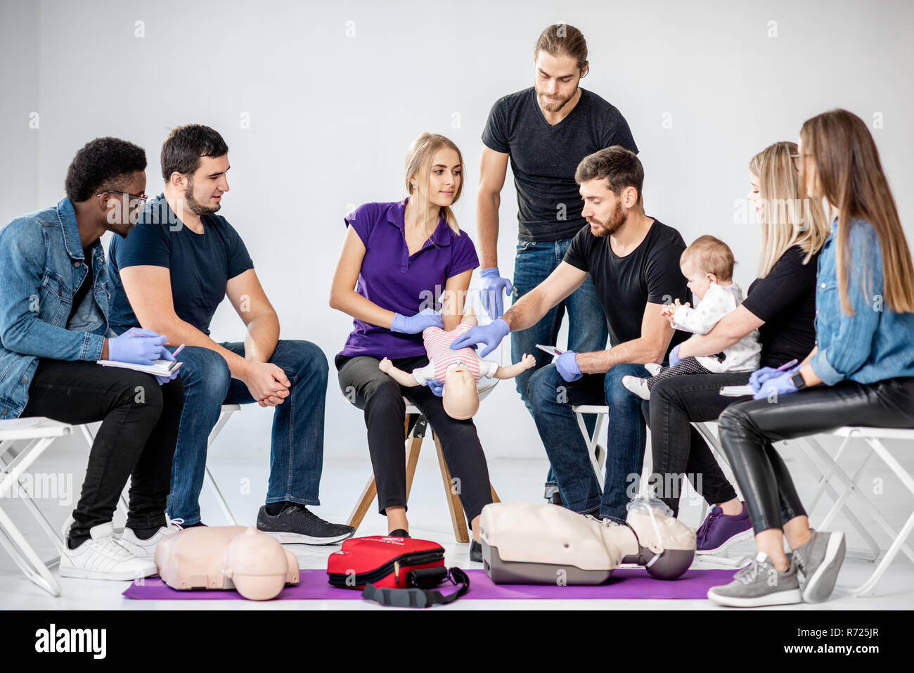 Groupe de personnes au cours de la formation en premiers soins avec moniteur montrant sur mannequin comment faire la respiration artificielle pour le bébé Banque D'Images