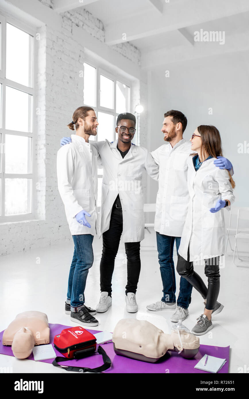 Portrait d'une jeune équipe de médecins en uniforme se tenant ensemble avec des choses après la formation en premiers soins dans la classe blanche Banque D'Images