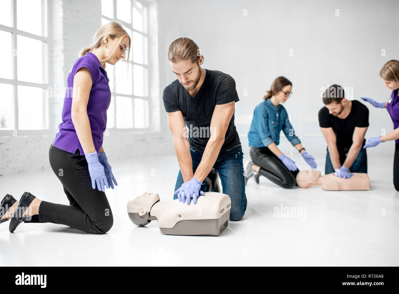 Groupe de jeunes de faire pratiquer la respiration artificielle avec des nuls au cours de la formation aux premiers secours dans la chambre blanche Banque D'Images
