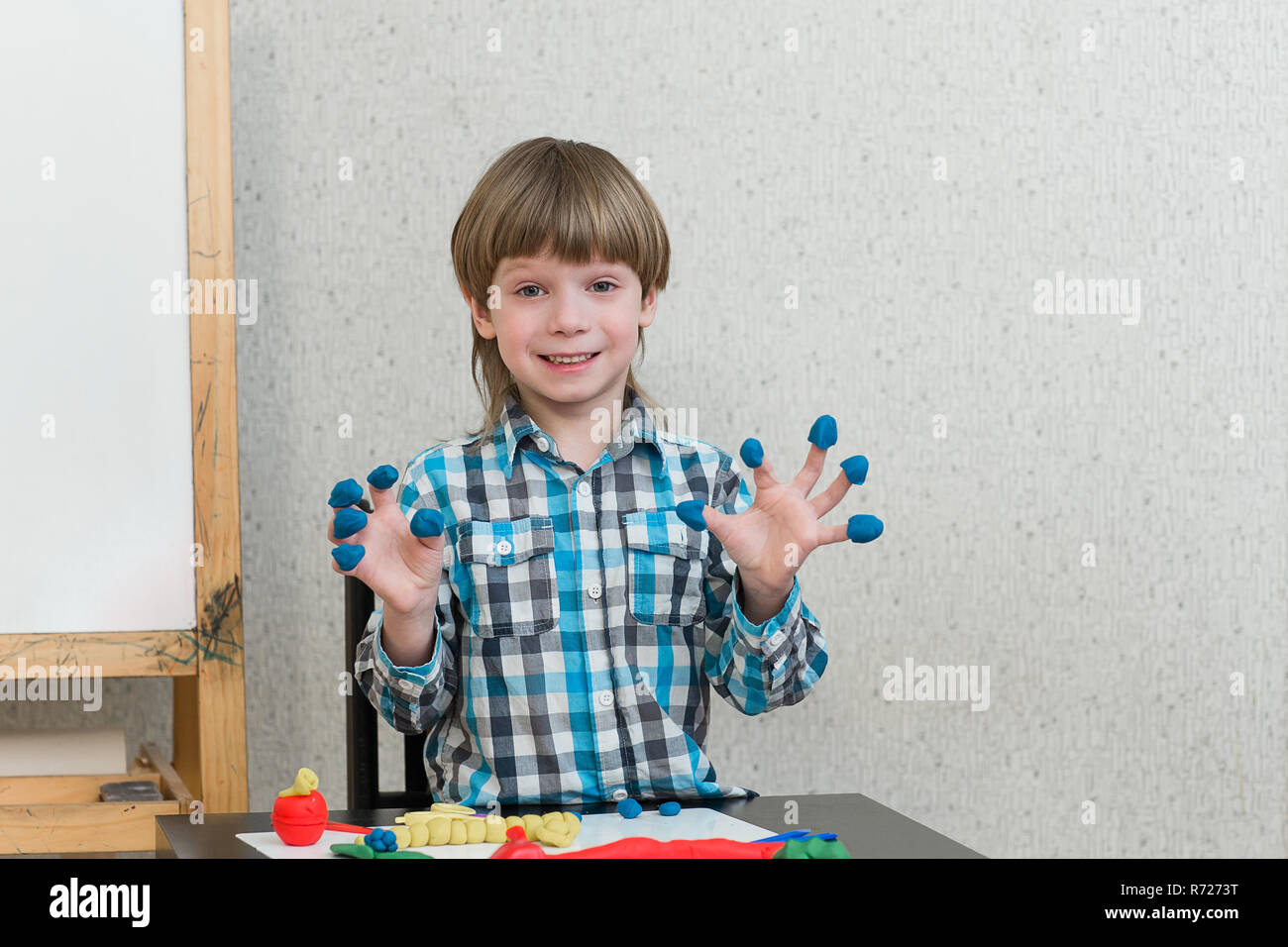 Garçon Blond sculpte à partir de pâte à modeler à la maison à la table. L'idée et concept de l'école, l'école, la maison de l'éducation et activités de développement. Banque D'Images