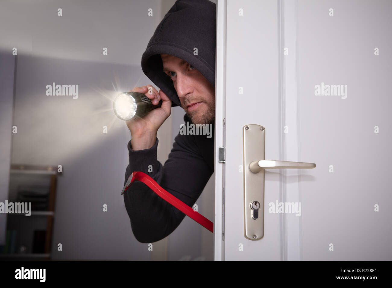 Voleur avec lampe et Crowbar Peeking de porte Banque D'Images