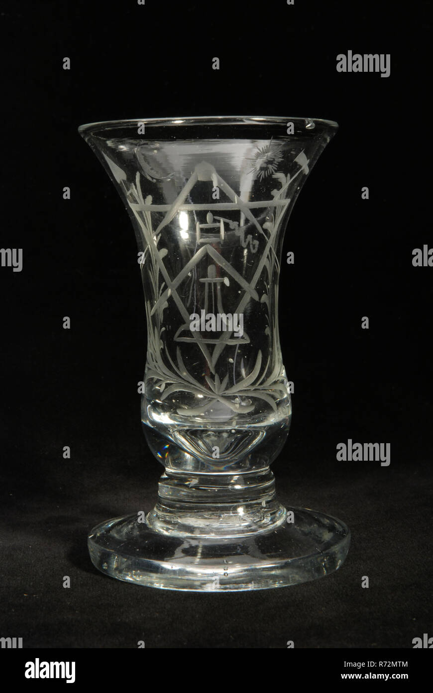 Verre sur pied (kanonglas) gravé de symboles maçonniques, verre à boire des verres de table en verre au plomb porte-verre, grammes de fondu et formé radgraving petit verre à pied (soi-disant) canonglas en verre au plomb, clair et incolore Pontil marque en vertu de l'épaisseur de la lumière creuse pied croissant sur une vente à fond arrondi et l'extension vers le calice avec grosse bulle d'air en pieds épais et fire-bord arrondi. Calice de gravure de roue avec symboles maçonniques : triangle carré passant à l'aplomb du crochet truelle niveau marteau spit soleil et lune des deux côtés entouré par des branches de palmier la franc-maçonnerie Banque D'Images