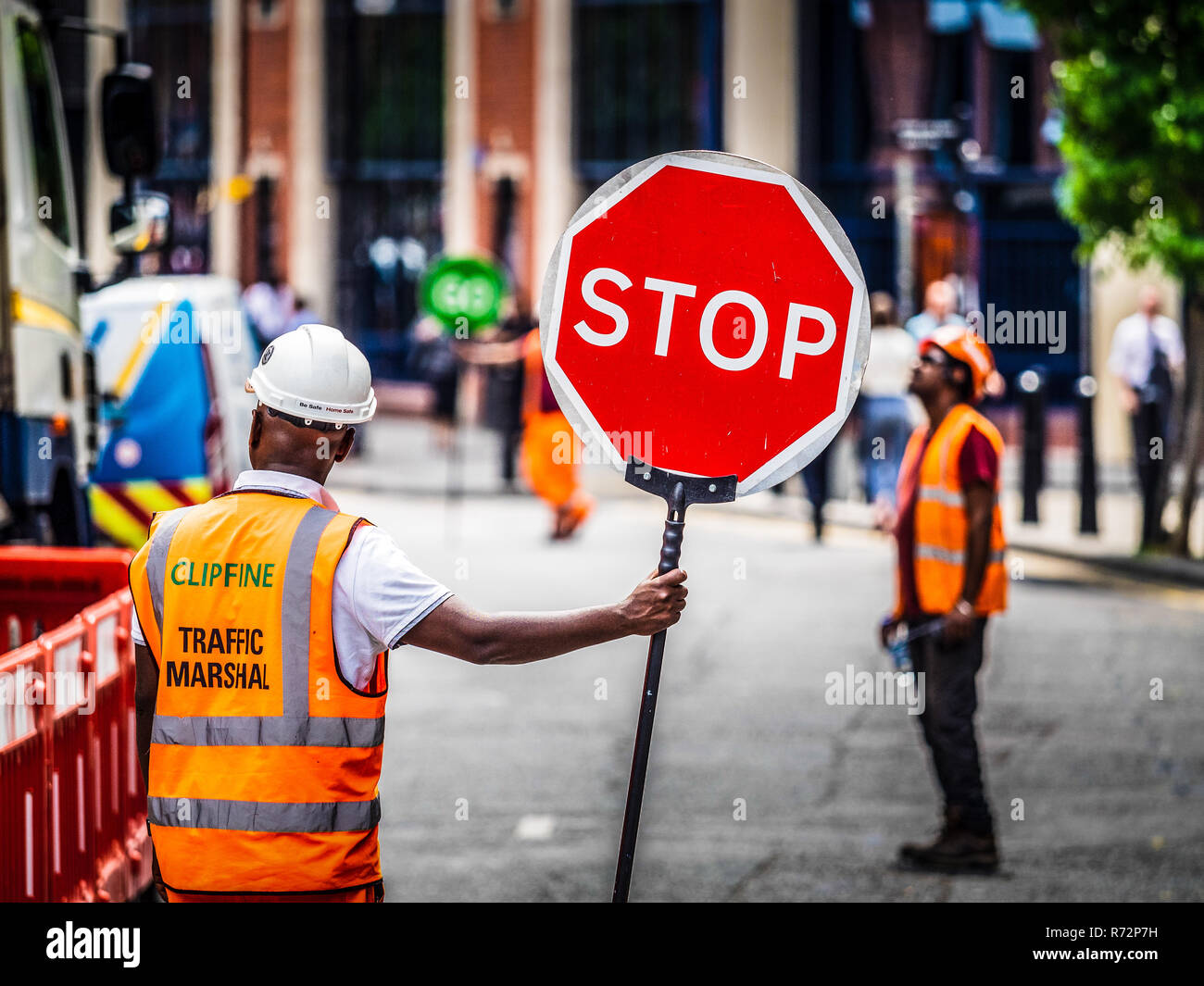 Bâtiment site Traffic Marshalls sur un site de bâtiment dans le centre de Londres avec les panneaux Stop Go. Banque D'Images