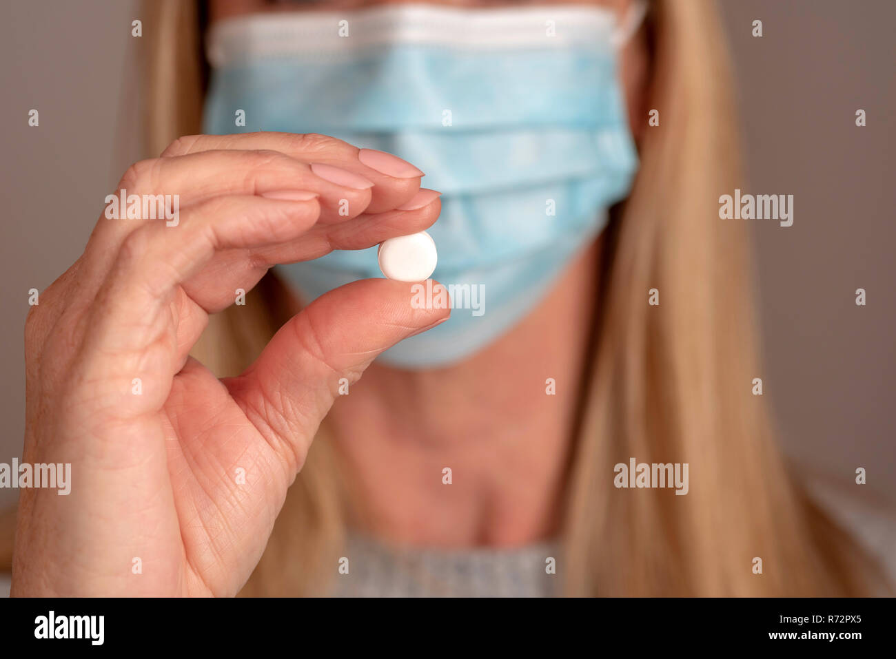 Femme portant un masque tenant une tablette prescrit entre le pouce et l'index. Banque D'Images