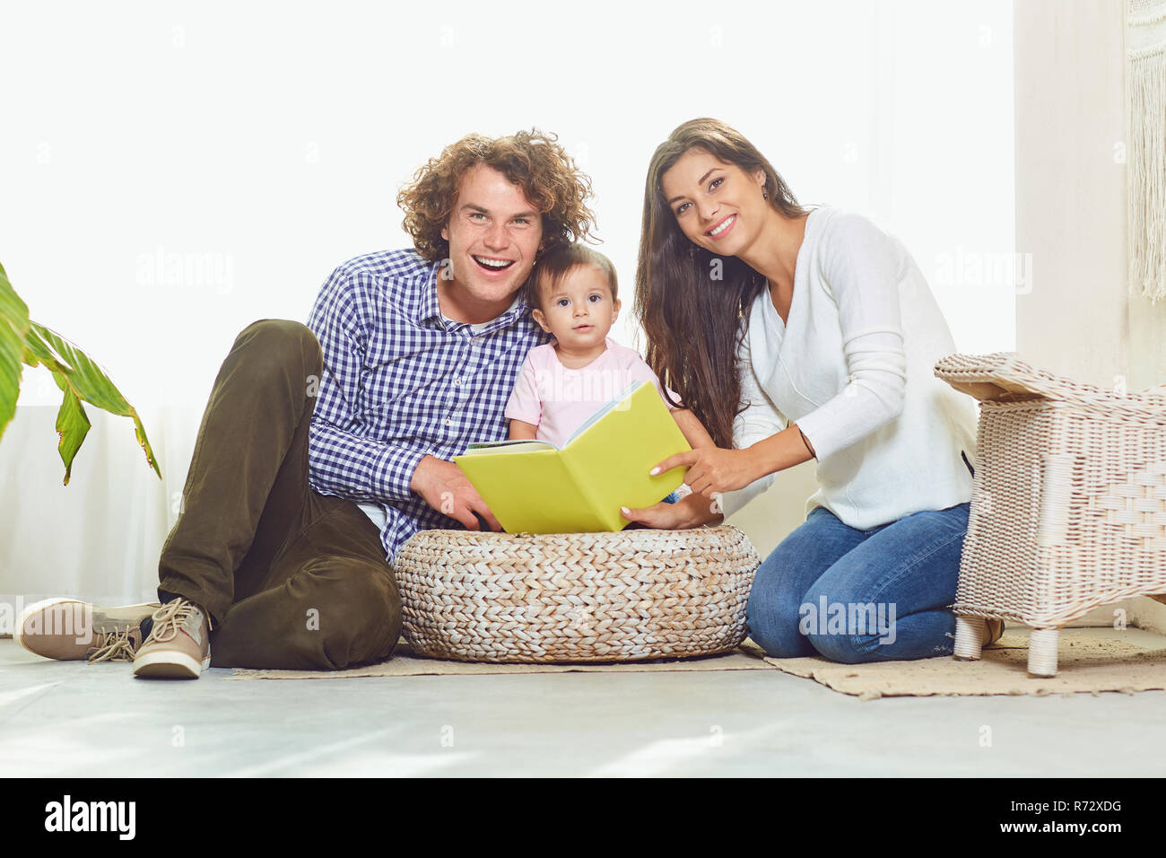 La mère, le père et l'enfant sont la lecture d'un livre à la maison Banque D'Images