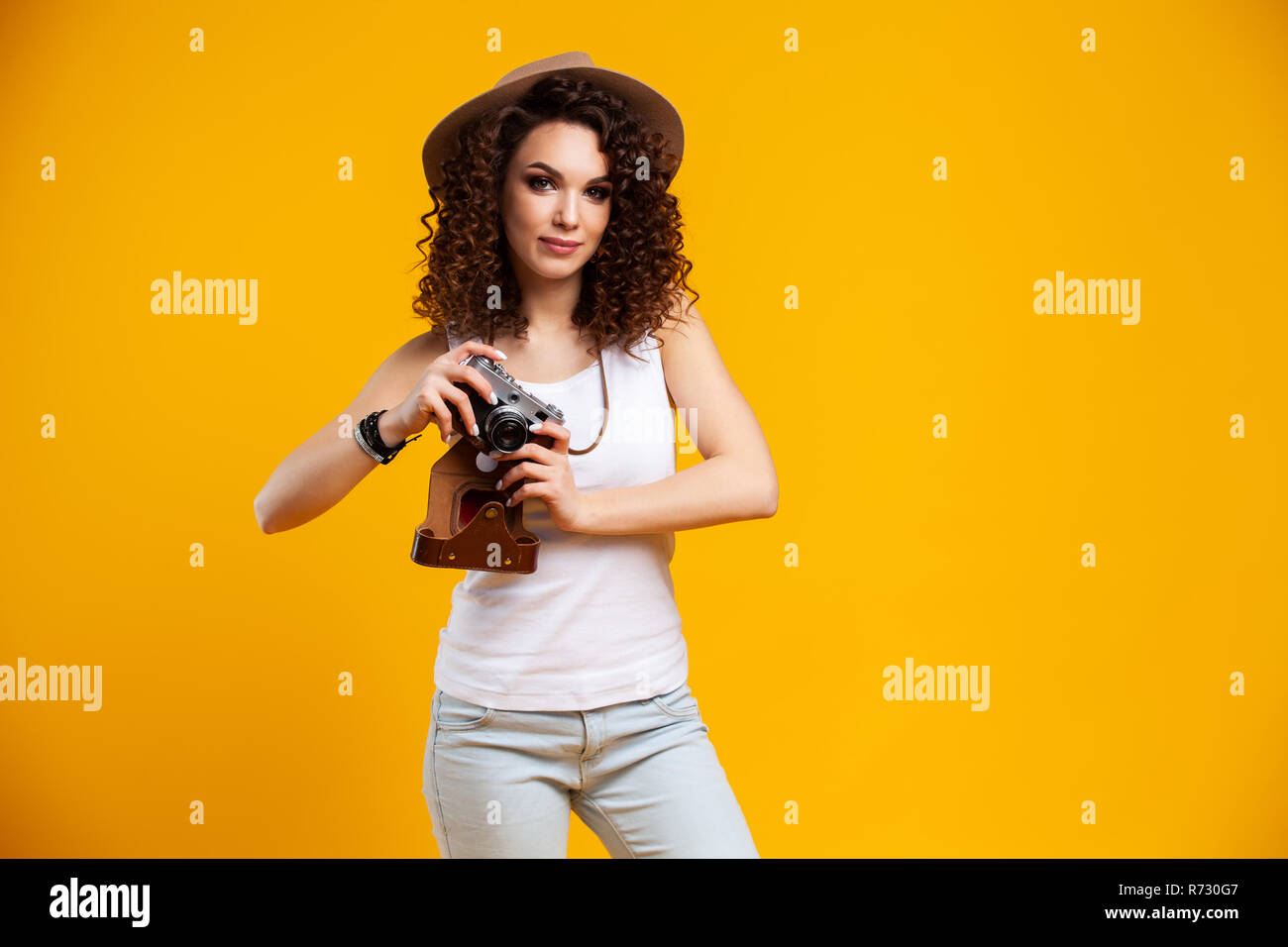 Portrait of laughing young woman taking pictures on retro vintage photo caméra isolé sur fond jaune vif. Les gens sincères émotions, lifestyl Banque D'Images