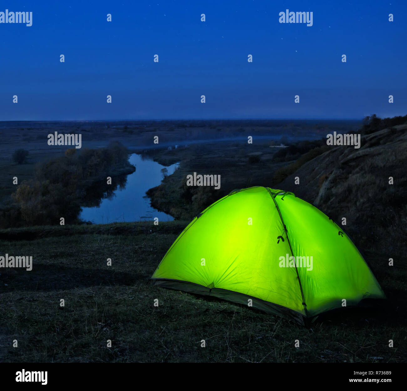 Courts de l'intérieur tente verte sur une colline au-dessus de la rivière. Paysage de nuit. Le concept de la liberté, la vie privée et les voyages. Banque D'Images