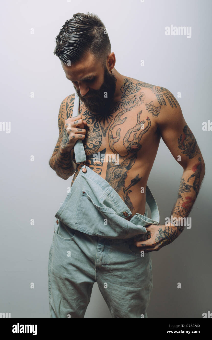 Portrait de jeune homme à porter des salopettes, torse nu couvert de  tatouages Photo Stock - Alamy