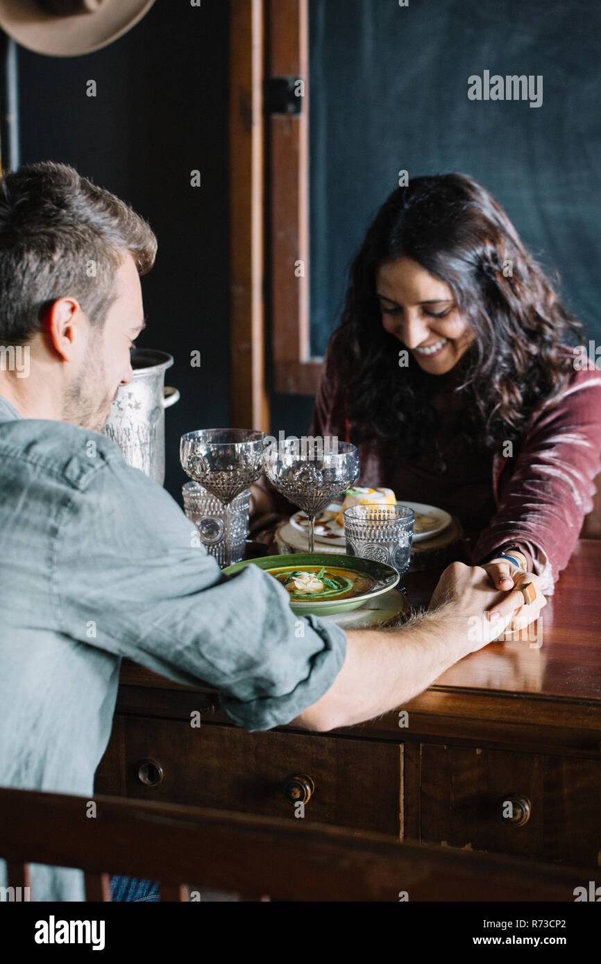 Couple ayant un repas, tenir la main à travers le tableau Banque D'Images