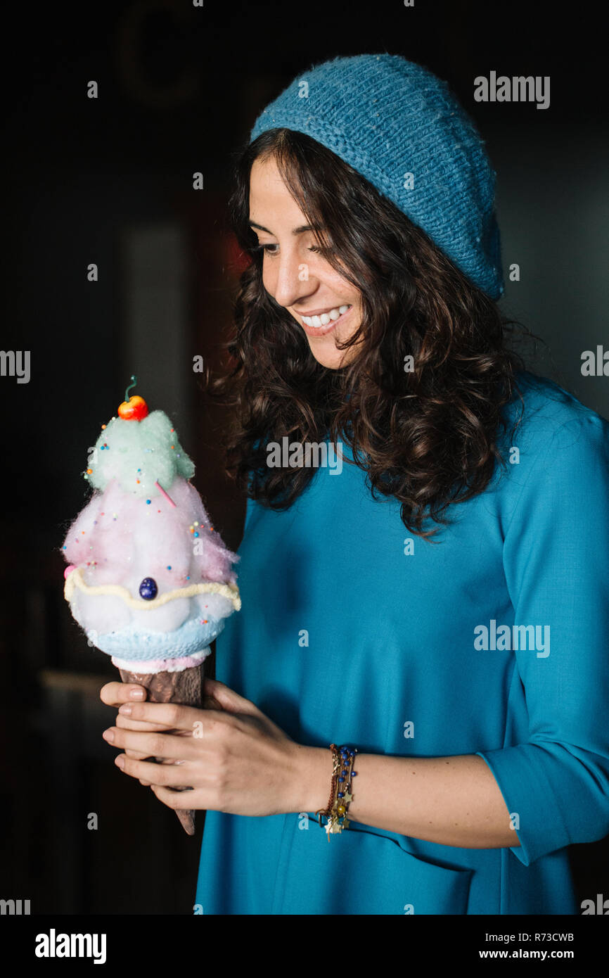 Jeune femme élégante en bleu Knit hat holding large ice cream cone Banque D'Images