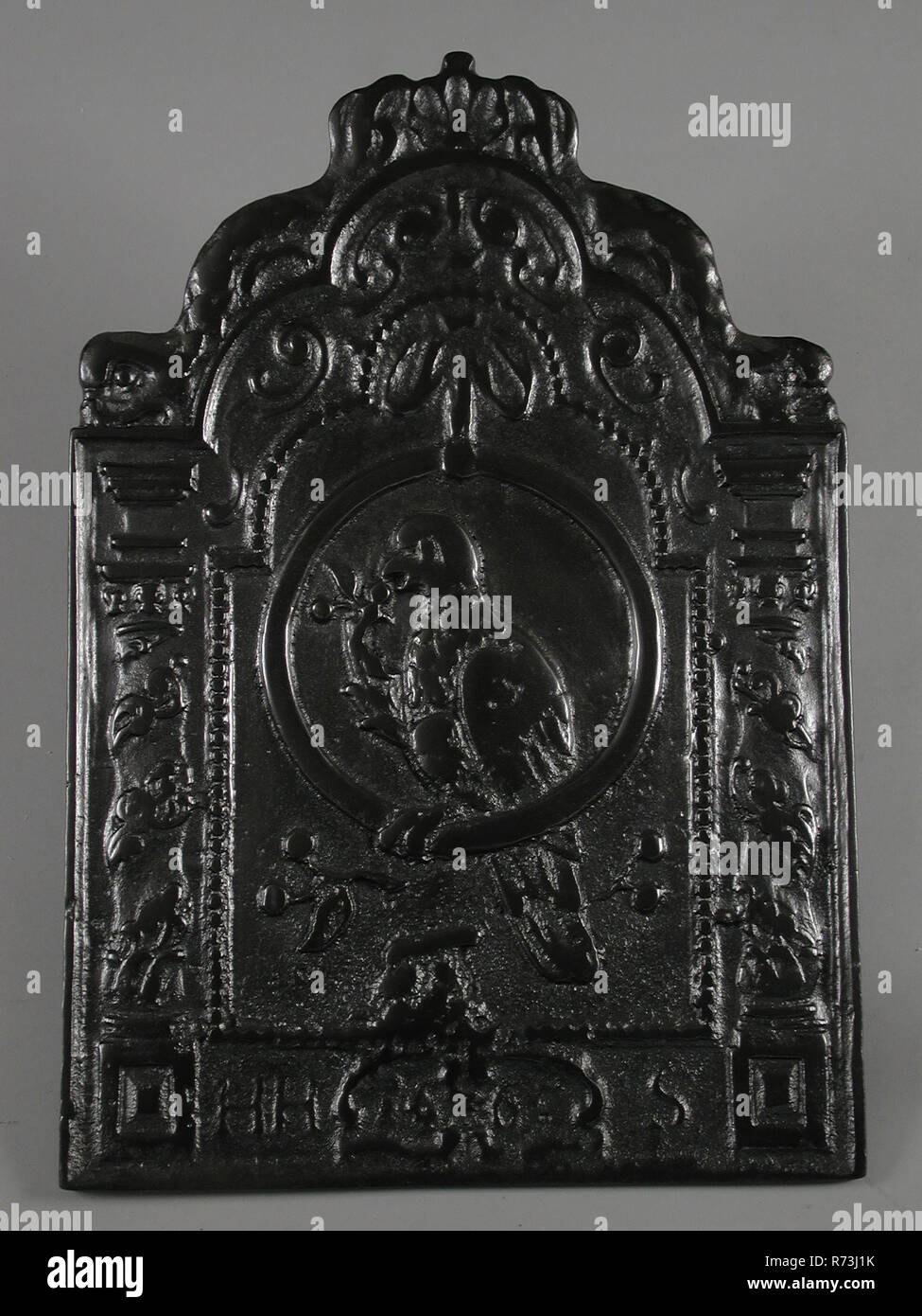 Dans l'anneau, Parrot faisan à HHS et de l'année 1665 texte, une plaque de cuisson en fonte, plaque de cuisson rectangulaire en fonte avec noeud au milieu parrot avec branche avec des baies. Autour de la frontière entre le châssis et le large collier de perle dans lequel pilastres torsadés avec décoration de feuilles haut au milieu coquille flanquée de deux dauphins et le châssis avec texte En Bas : Bas de l'année 1665 et HHS (mal lisible) vivant à l'intérieur de l'environnement chauffage Banque D'Images