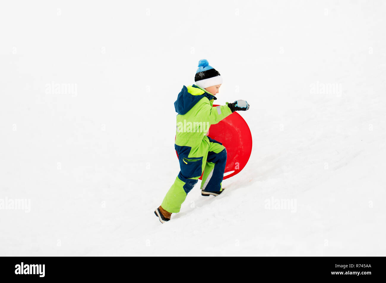 Happy boy avec de la neige en hiver luge soucoupe Banque D'Images