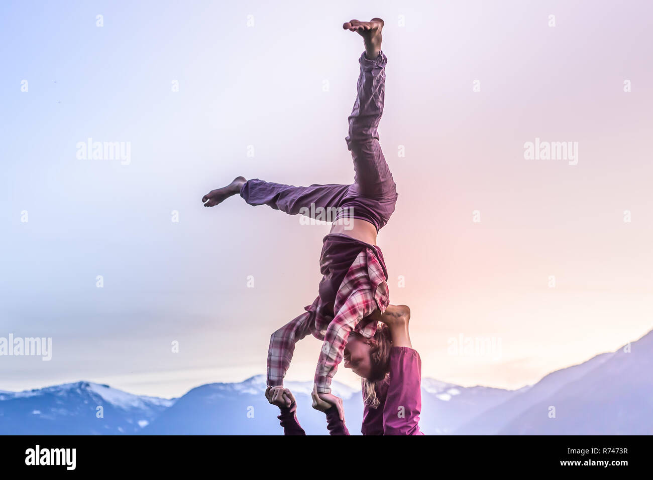 Deux jeunes femmes pratiquant acroyoga en face de montagne au coucher du soleil, Squamish, British Columbia, Canada Banque D'Images