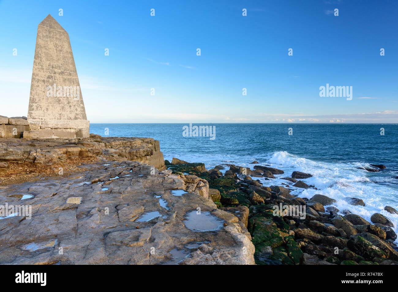 Les vagues déferlent sur la côte rocheuse de la côte jurassique du manche en vertu de la Trinity House obélisque marquant la pointe de Portland Bill dans le Dorset. Banque D'Images