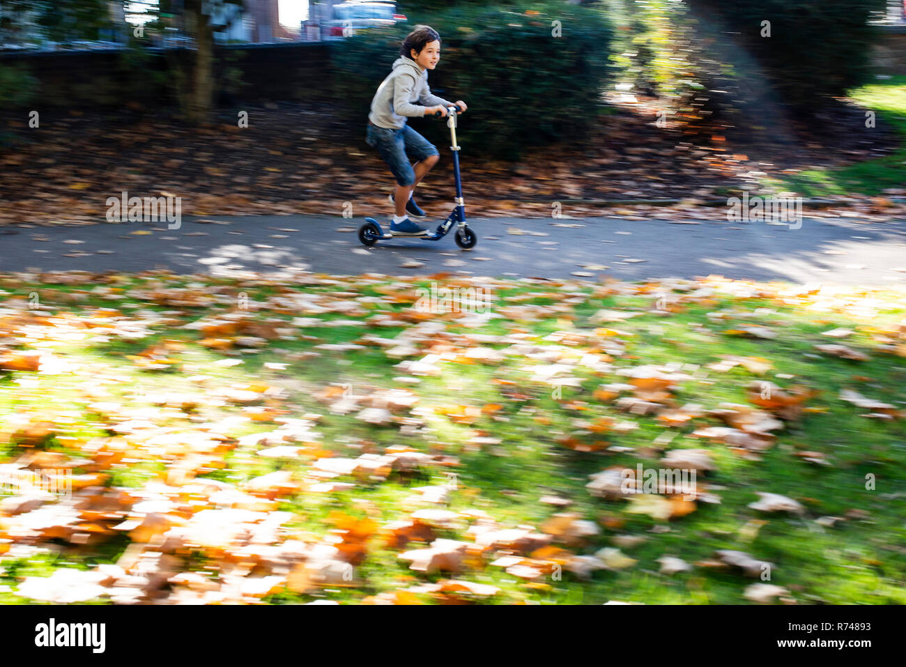 Boy riding scooter push in park Banque D'Images