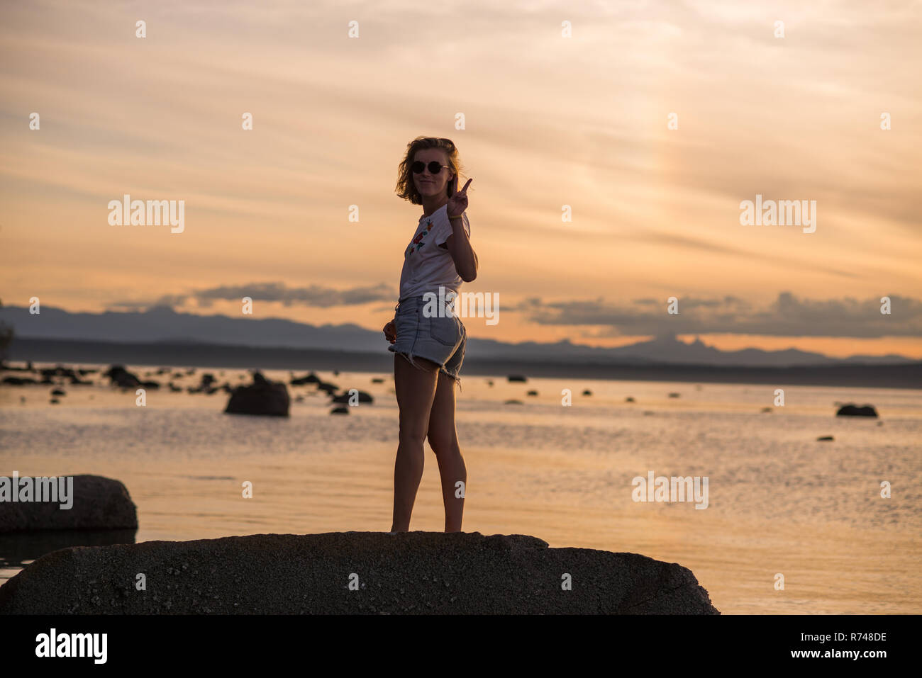 Jeune femme debout sur le roc au coucher du soleil, portrait, Quadra Island, Campbell River, Canada Banque D'Images
