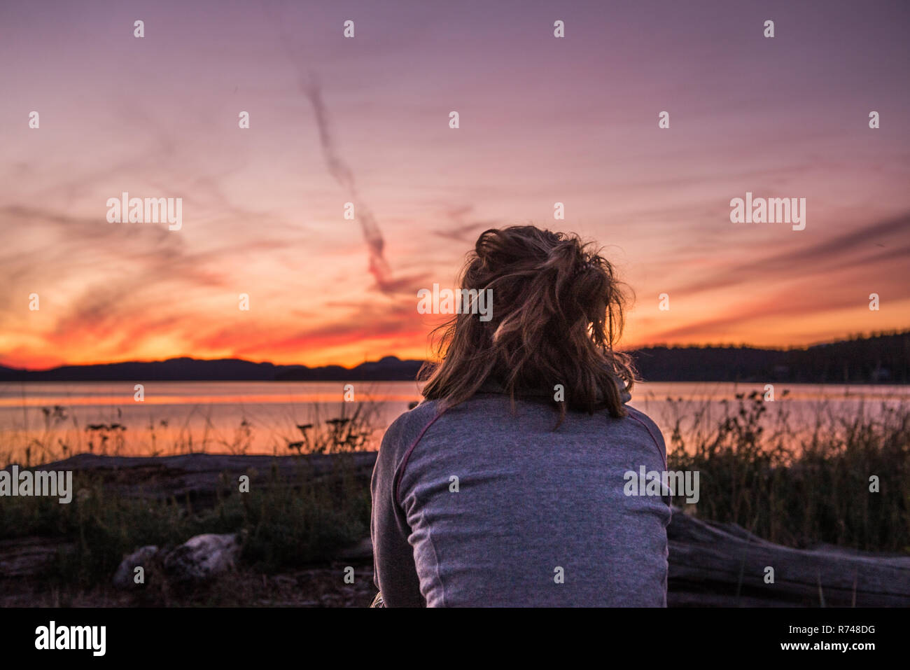 Jeune femme regardant au coucher du soleil, vue arrière, Quadra Island, Campbell River, Canada Banque D'Images