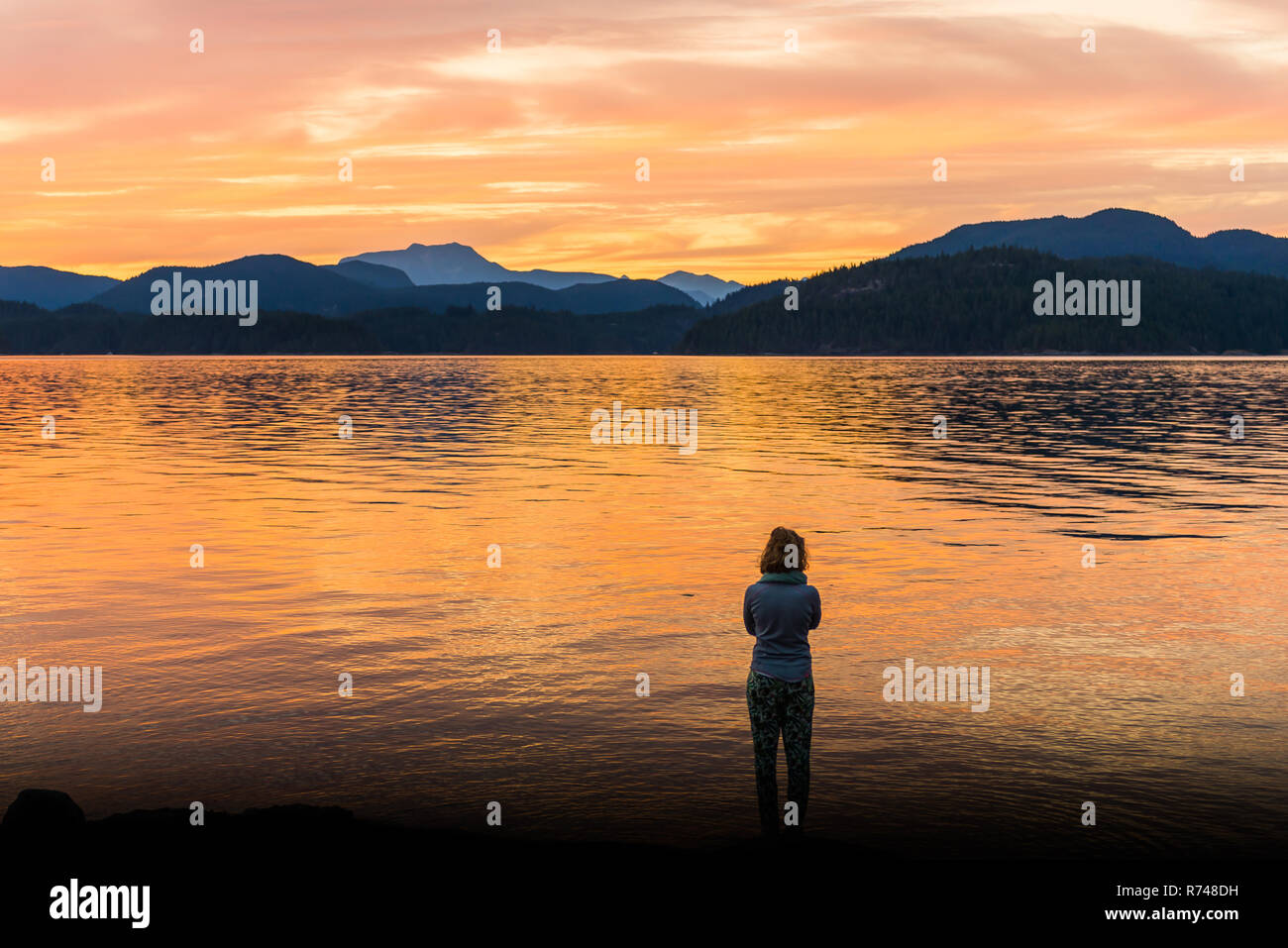 Jeune femme regardant au coucher du soleil, l'île de Quadra, Campbell River, Canada Banque D'Images