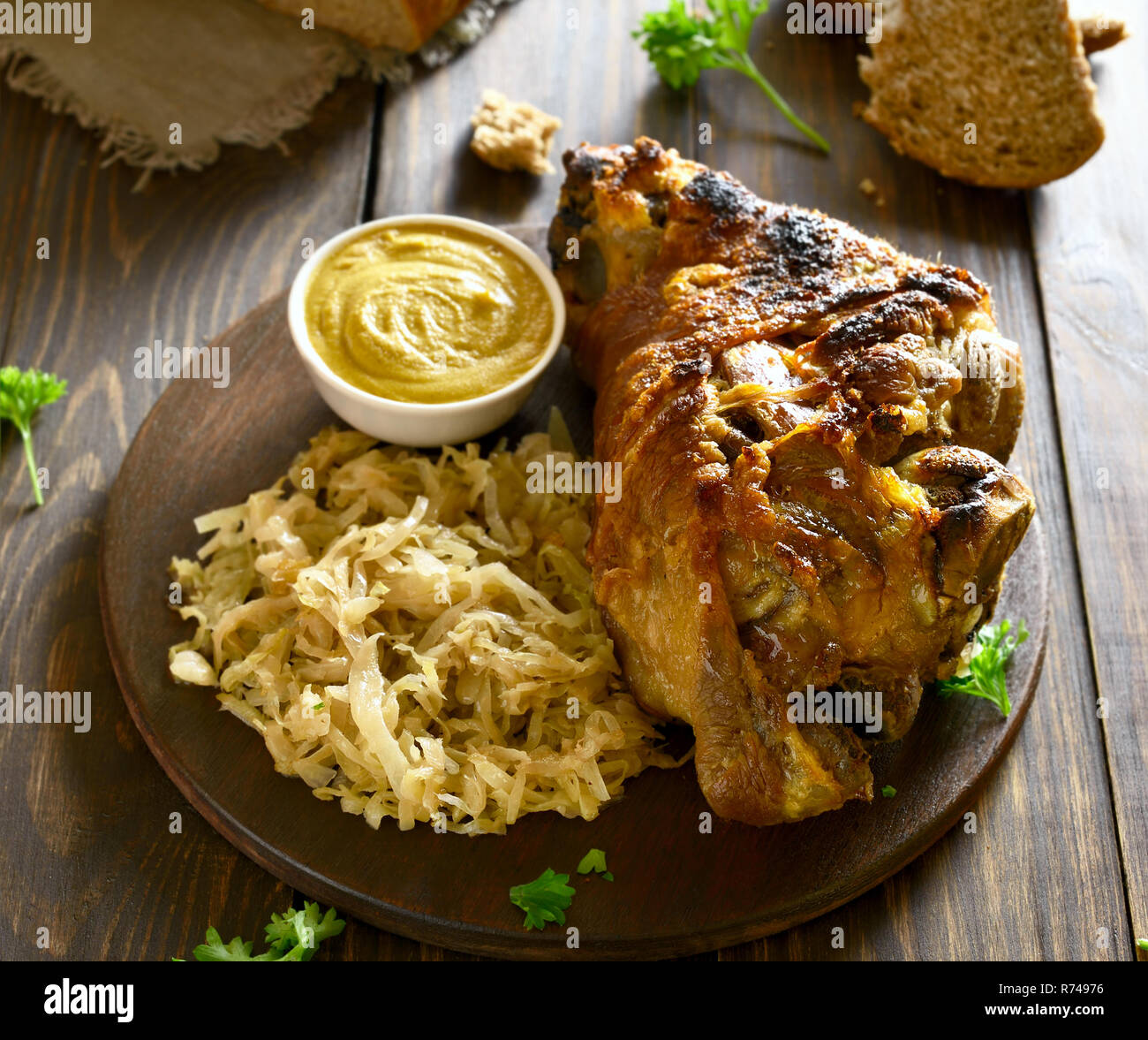 Jarret de porc (eisbein au four) avec du chou braisé (choucroute) et de la moutarde sur table en
