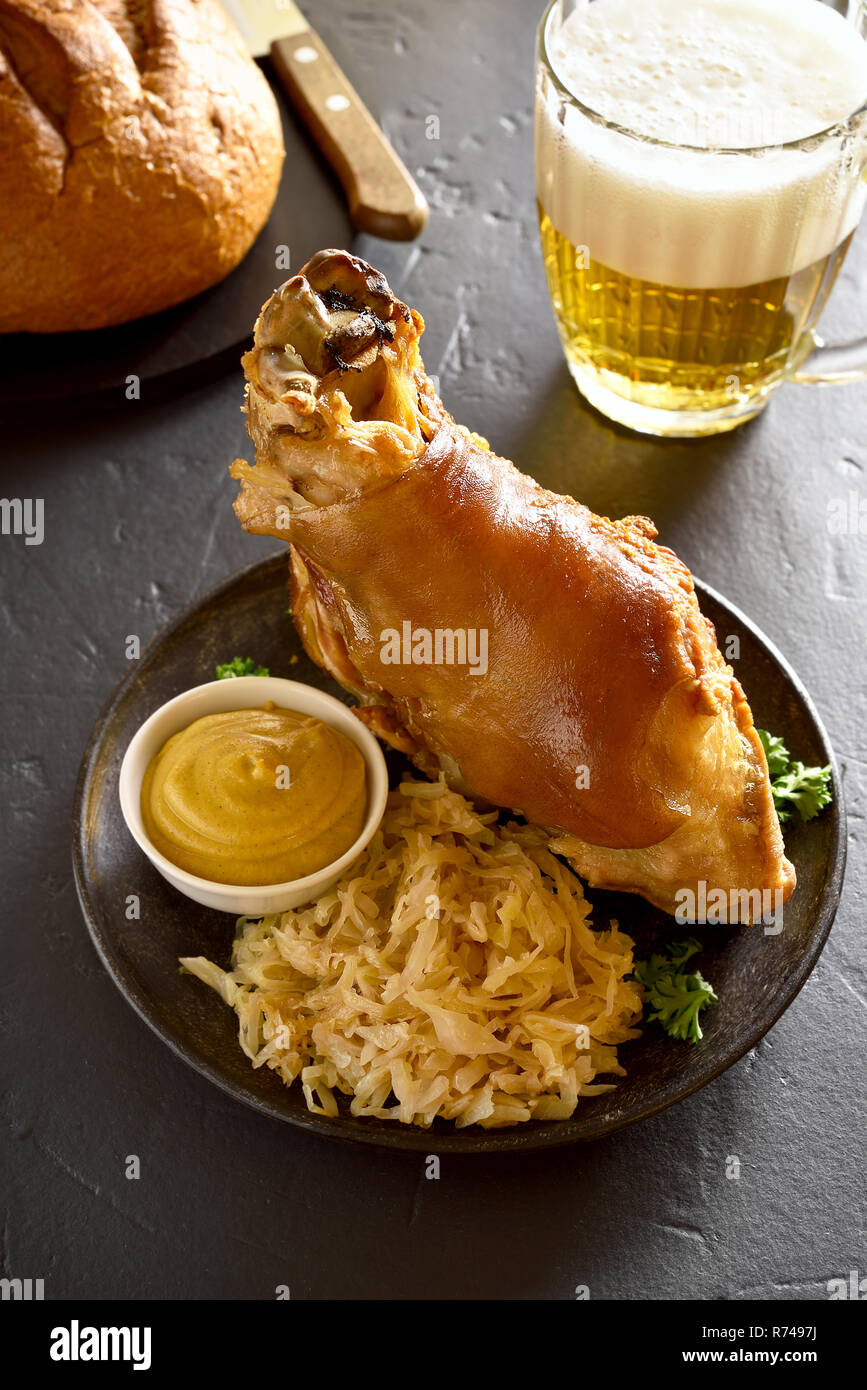 Jarret de porc rôti (eisbein) avec du chou braisé (choucroute) et de la moutarde sur table en