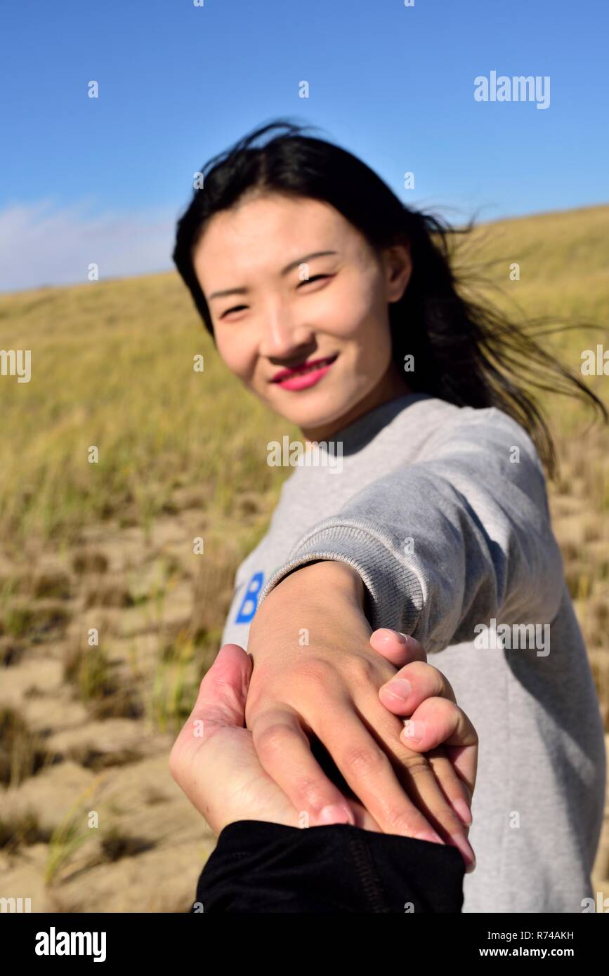 Un homme de race blanche qui tient la main de belle femme chinoise sur les dunes de Cape Cod dans le Massachusetts sur une journée ensoleillée d'automne. Banque D'Images