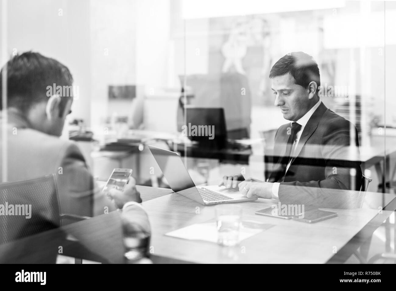 Deux jeunes hommes d'utiliser un ordinateur portable lors de réunions d'affaires. Banque D'Images