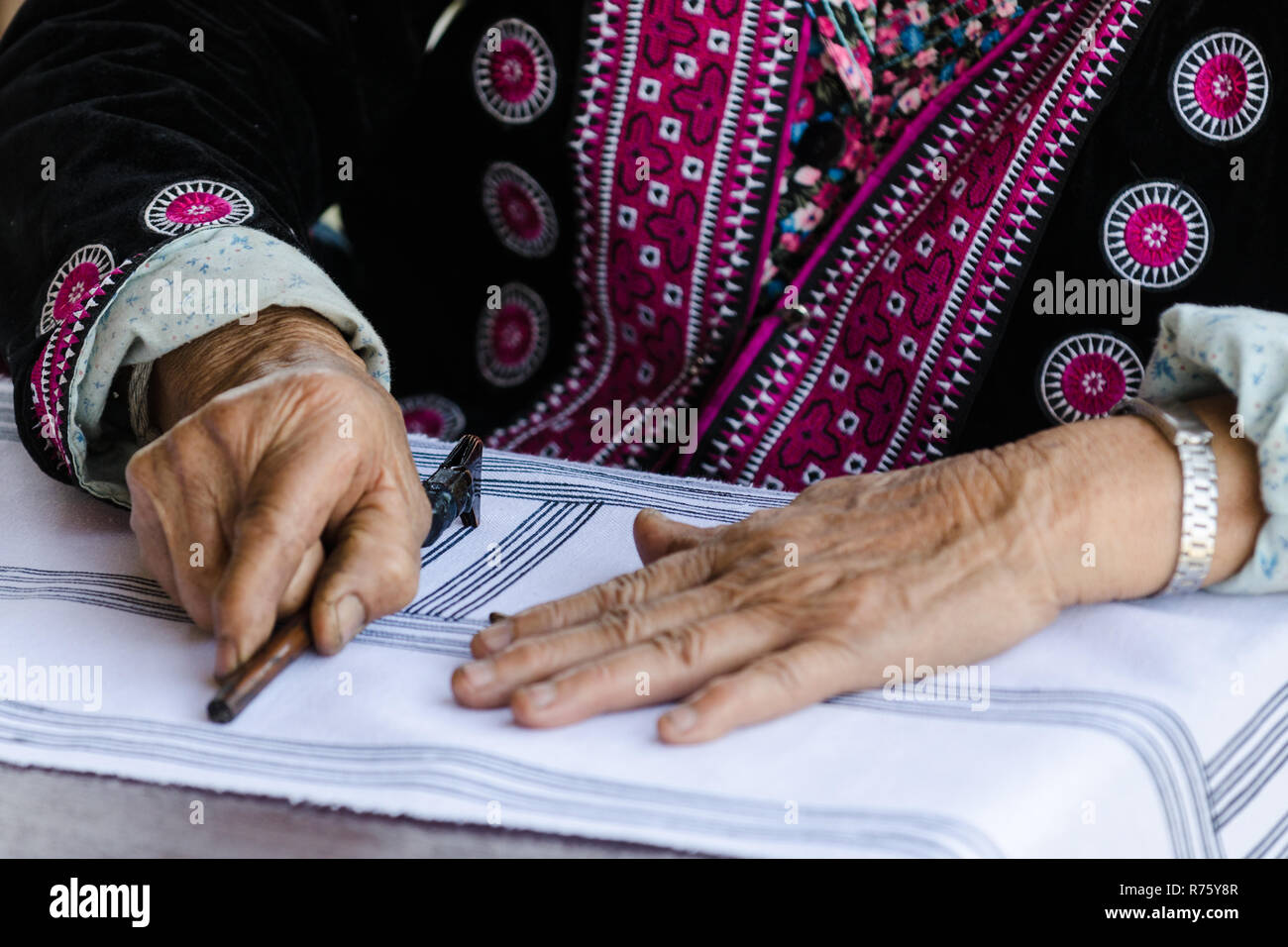 Close up d'une vieille femme Hmong's hands design patterns dessin sur un tissu avec l'outil Tjanting, Baan Tong Luang, Thaïlande Banque D'Images