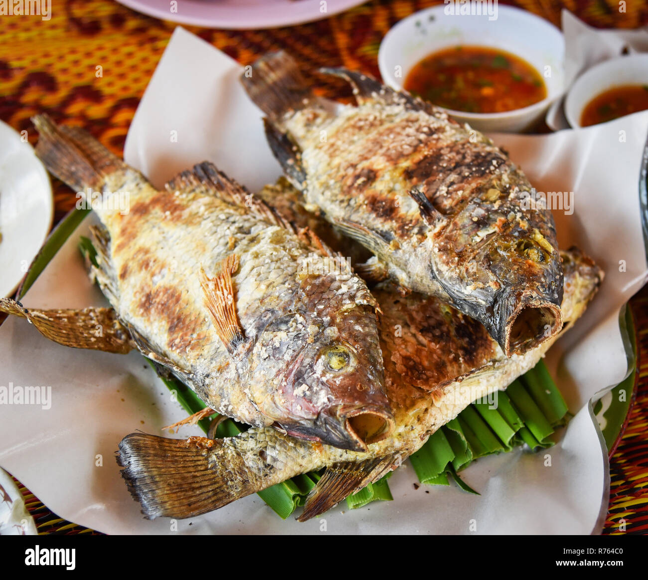 Grillades de poisson Tilapia tilapia grillé à l'/ Sel dans l'alimentation de style asiatique avec la sauce sur platine - poisson tilapia thaïlandais brûler herbes brûlées Banque D'Images
