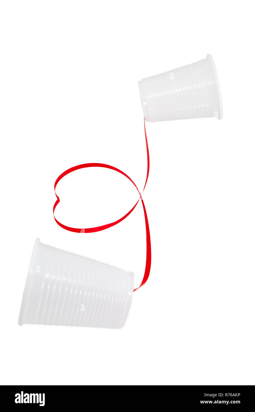 Relation à distance concept. 2 tasses en plastique blanc connecté avec un fil rouge Banque D'Images