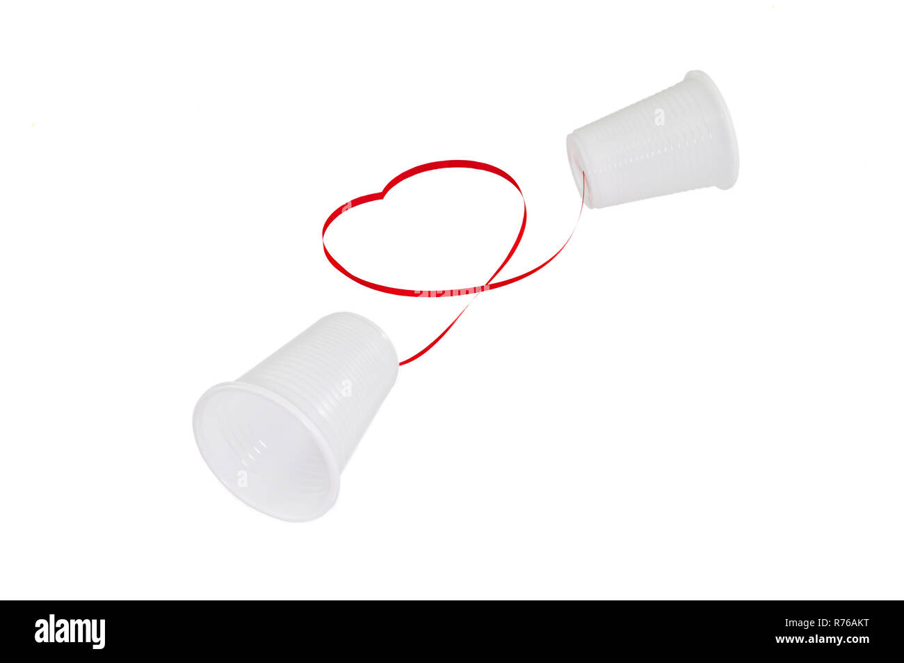 Relation à distance concept. 2 tasses en plastique blanc connecté avec un fil rouge Banque D'Images
