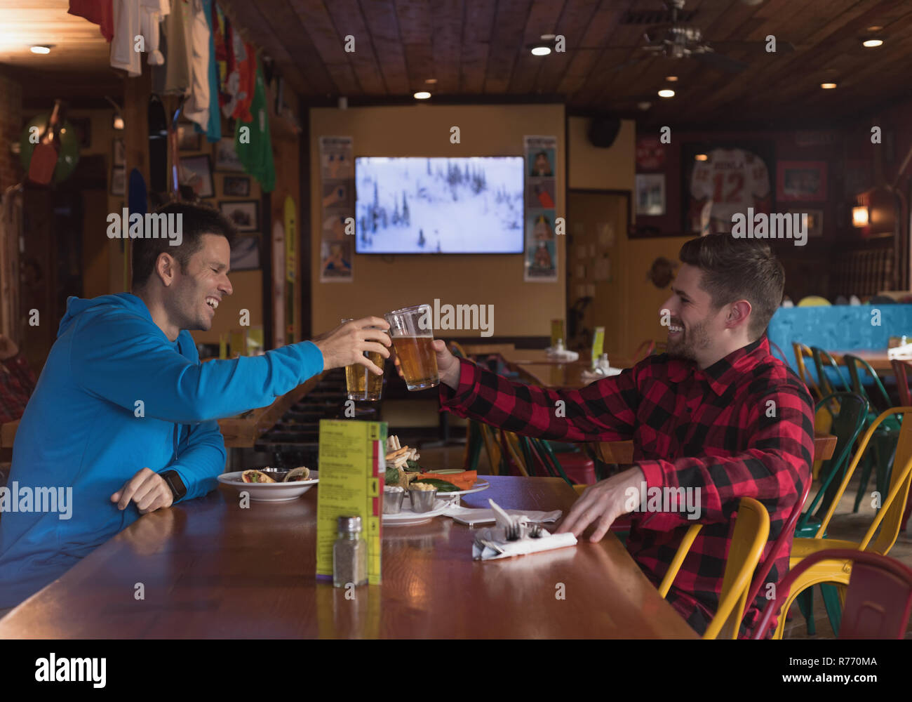 Friends toasting beer glasses in pub Banque D'Images