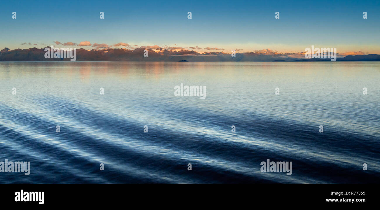 Les ondulations de la vague de proue de navire, du côté du Port, dans le quartier tranquille de lumière de l'aube avec sunrise allumé les montagnes. Stephen's Passsage, archipel Alexander, Alaska, USA. Banque D'Images