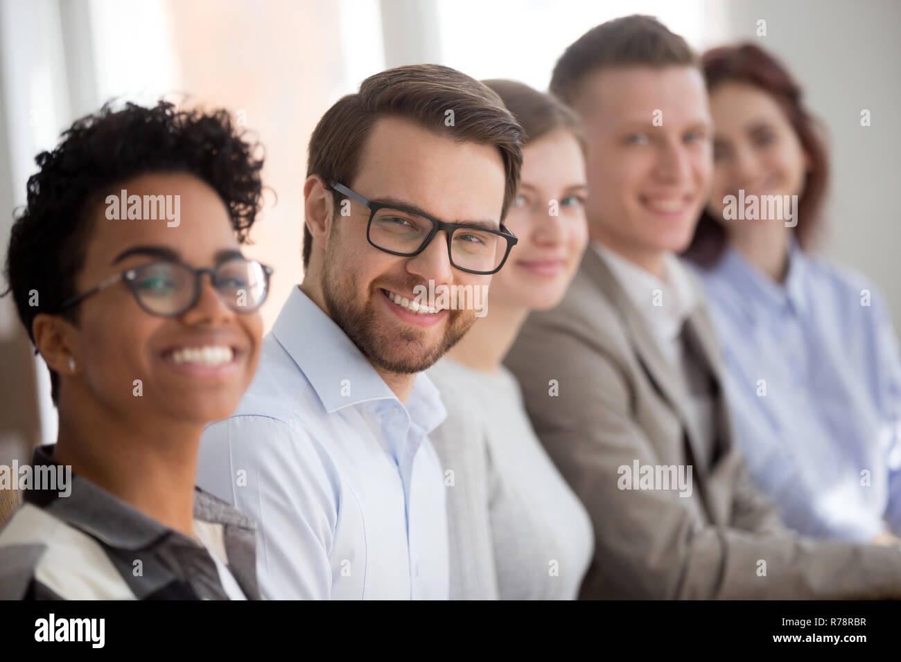 Portrait of smiling employés s'asseoir dans la rangée looking at camera Banque D'Images