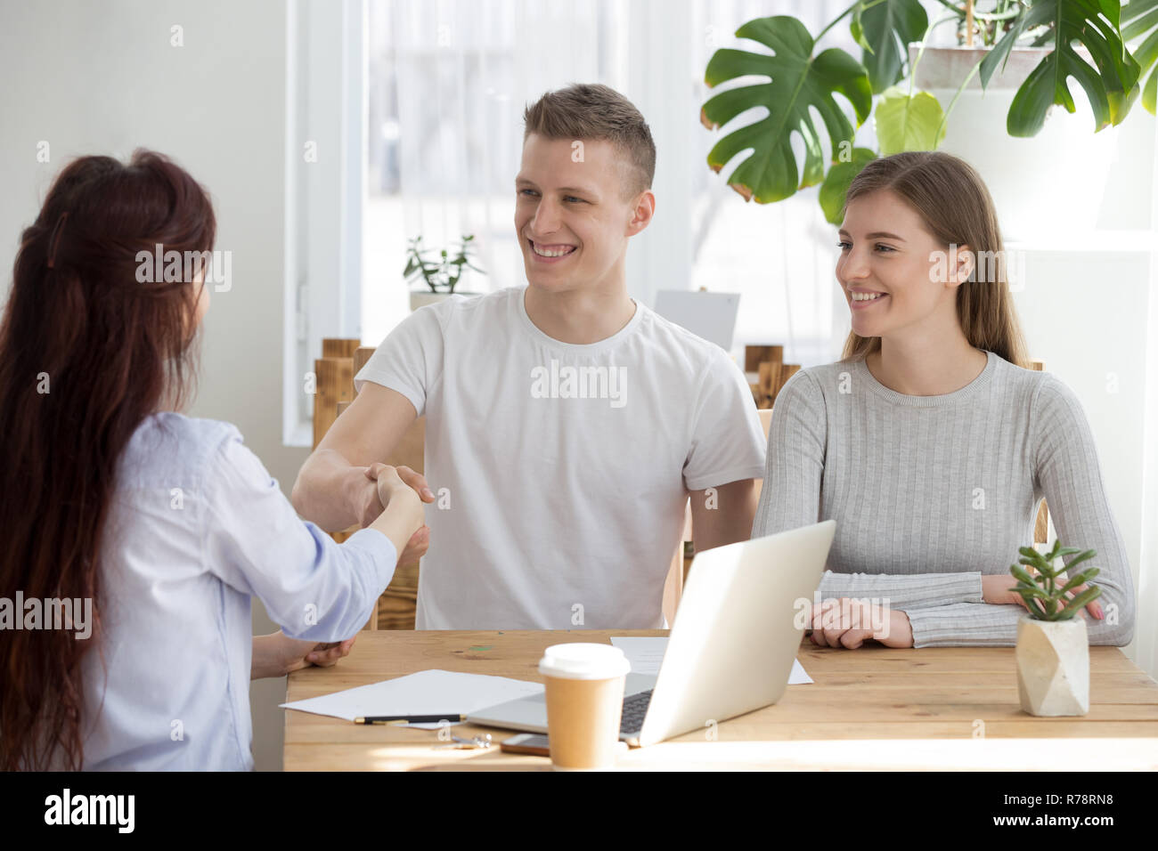 Heureux couple millénaire courtier handshake meeting in office Banque D'Images