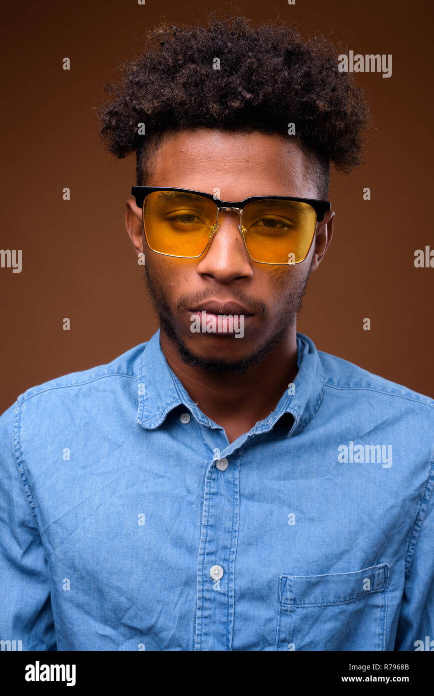 Visage de jeune beau homme africain contre fond brun Banque D'Images