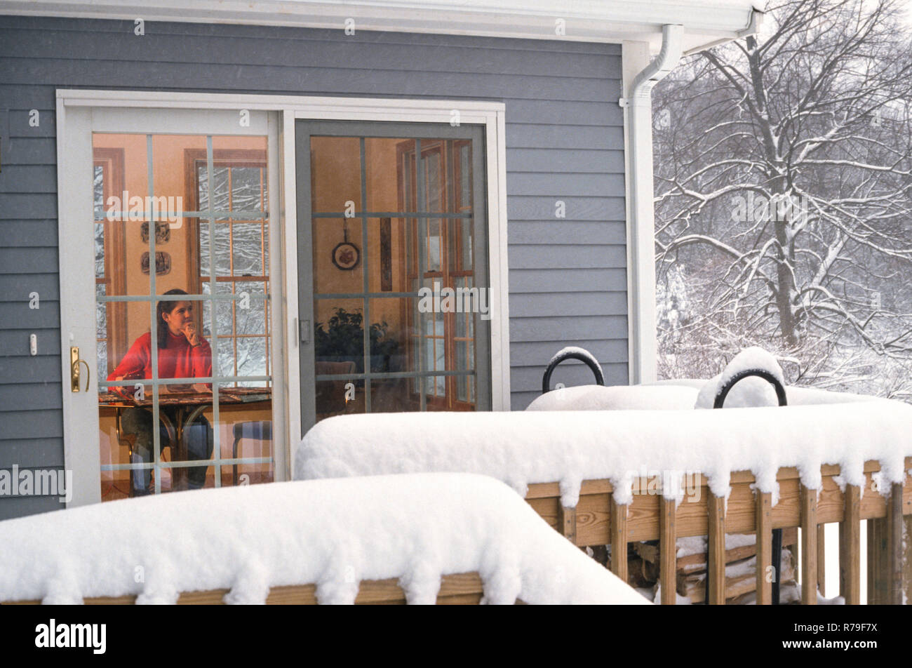 Jeune femme à l'intérieur d'une maison confortable dans une tempête, nord-est des États-Unis Banque D'Images