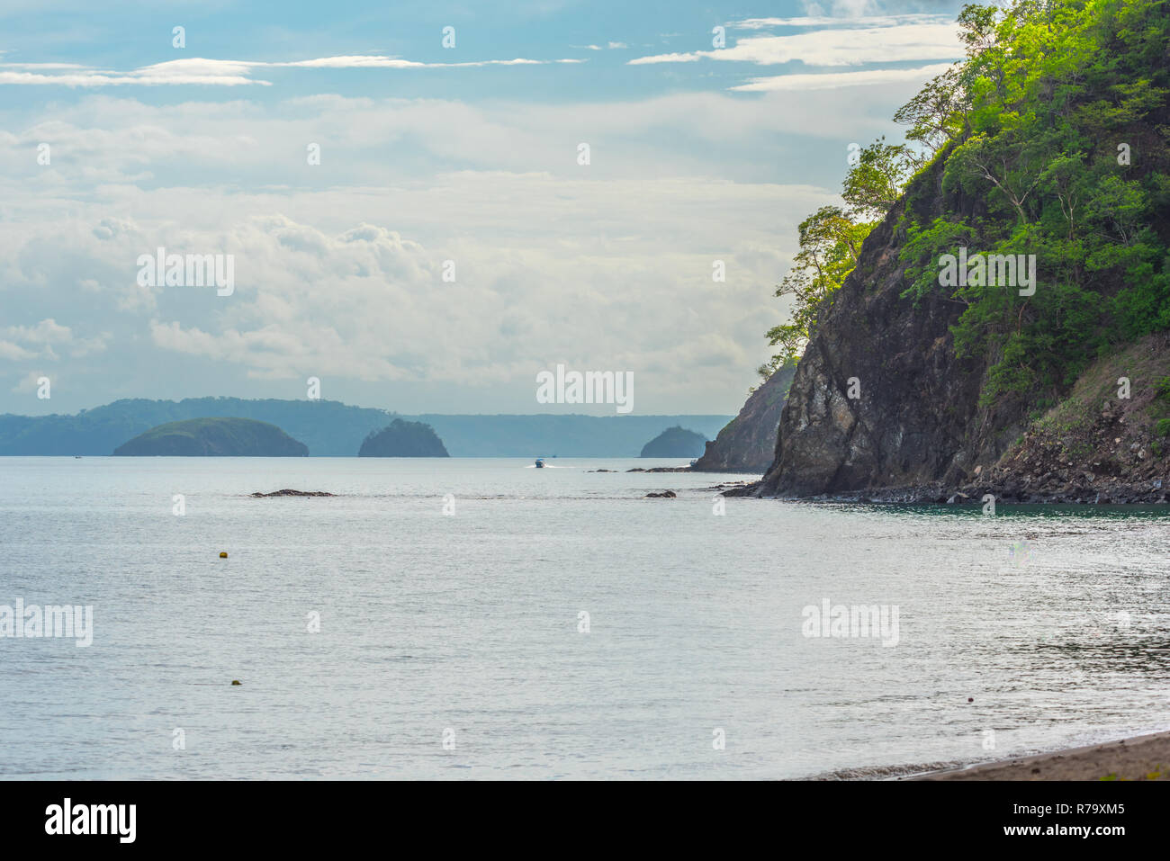 Le feuillage des arbres et se développer de très vieux rocher sur une pente raide, la hausse que les frontières qui affleurent une plage au Costa Rica. Bateau va le long de la côte rocheuse Banque D'Images