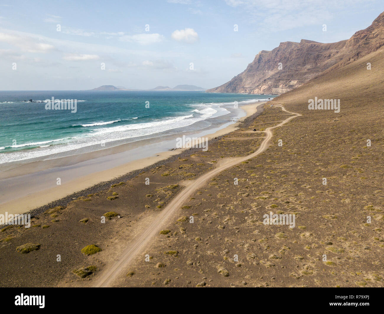 Vue aérienne de la plage de Famara, Lanzarote, îles Canaries, Espagne. Di Risco de Famara, relief, montagne surplombant l'océan Atlantique. Chemin de terre Banque D'Images